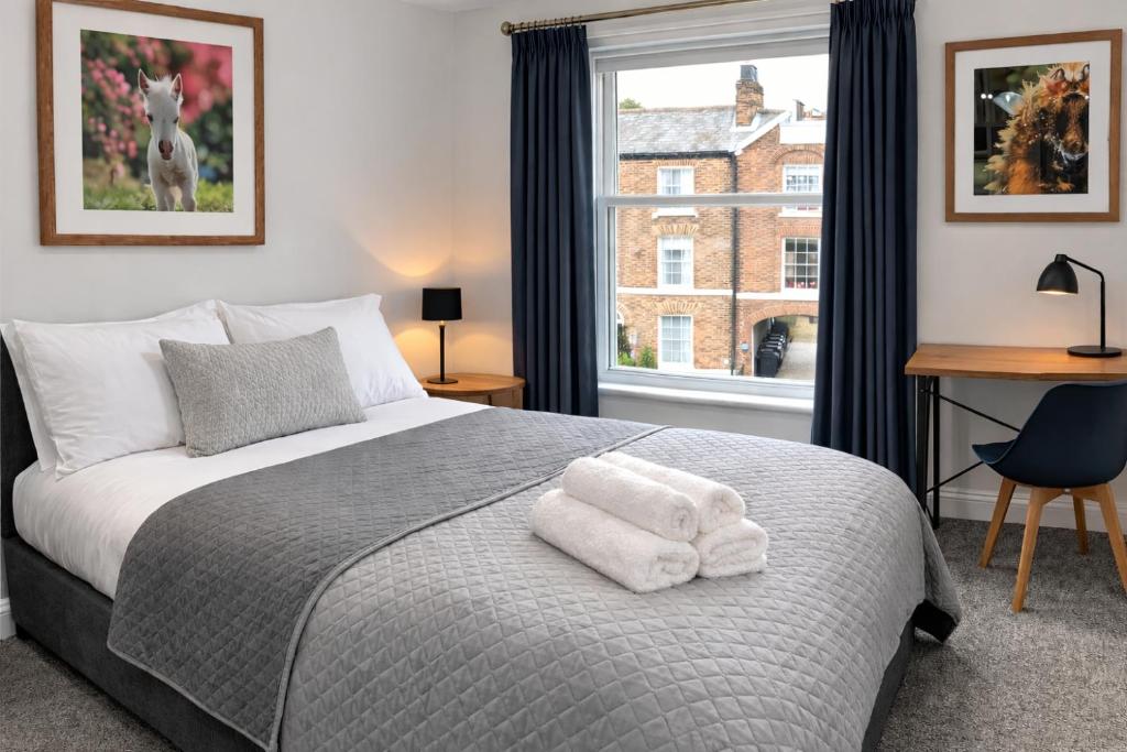 a bedroom with a bed with a desk and a window at Parkview Guest House in King's Lynn