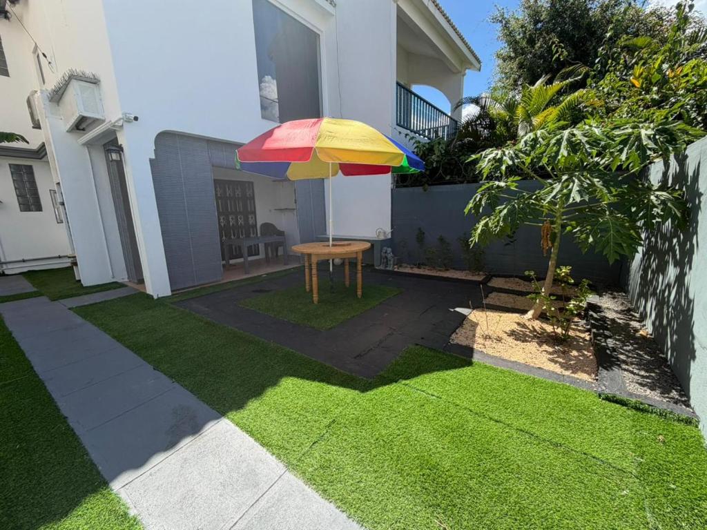 a patio with a table and a colorful umbrella at PRIBO's in Flic-en-Flac