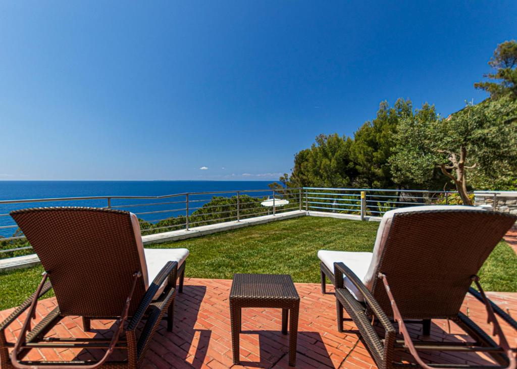 two chairs and a table on a patio overlooking the ocean at Villa Ritter Orizzonte in Cavoli