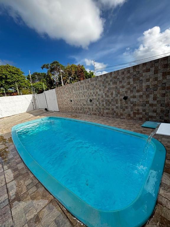 a blue swimming pool next to a brick wall at Casa em Jacumã in Conde
