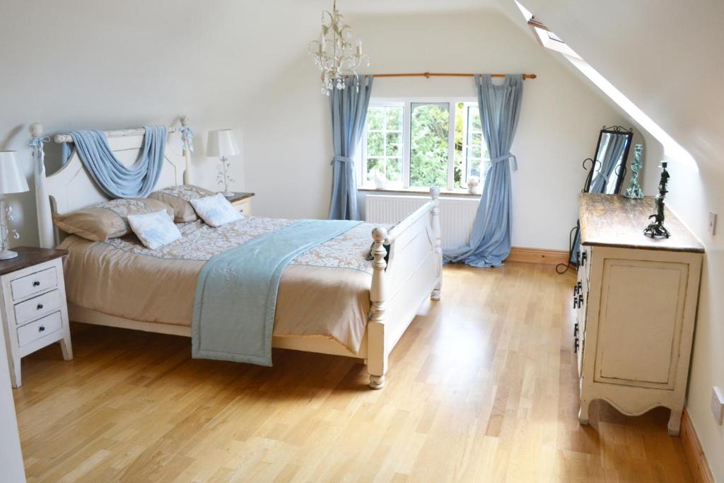 a bedroom with a large bed with blue curtains at Hook Head Guest House in Fethard on Sea