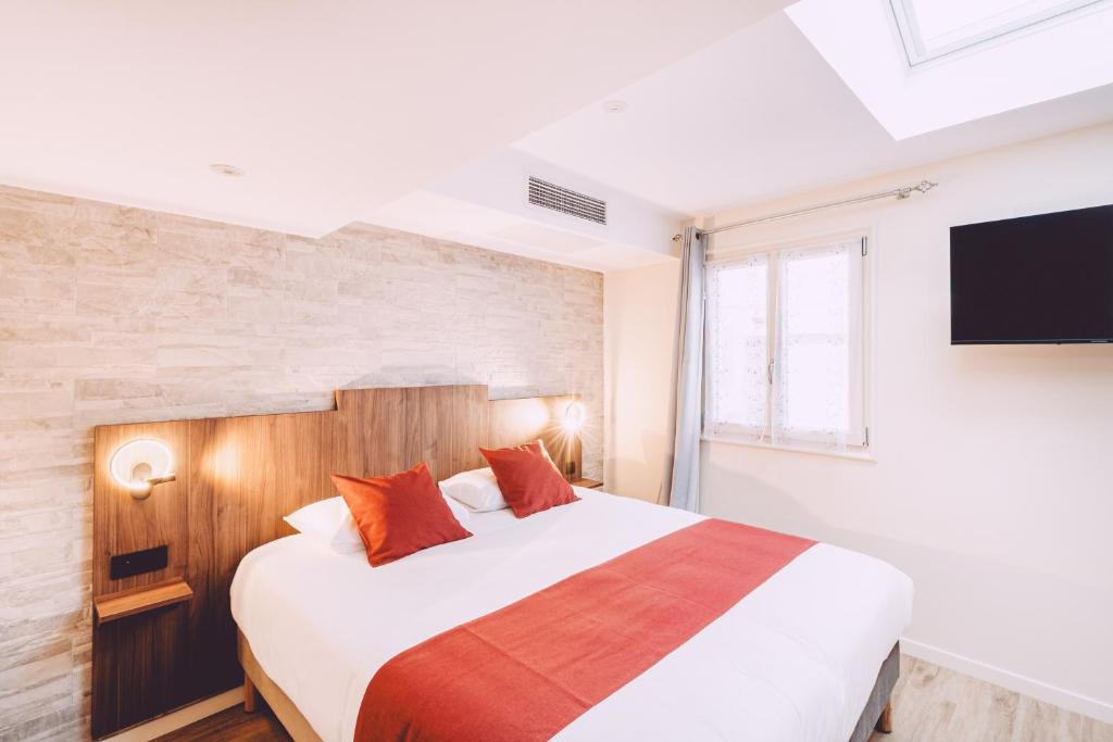 a bedroom with a large bed and a flat screen tv at Hôtel de la Poste in Chablis