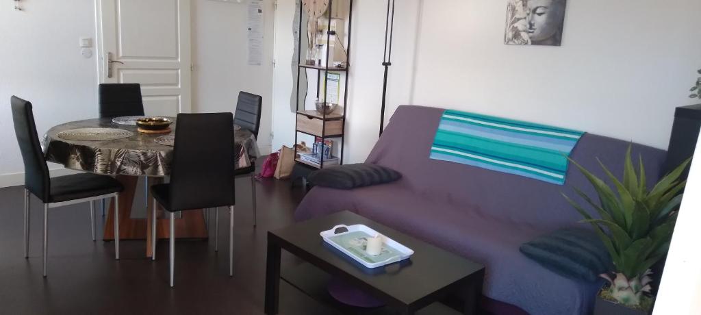a living room with a purple couch and a table at CHEZ JOSY in Gérardmer