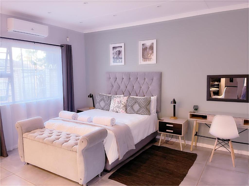 a white bedroom with a large bed and a chair at Clifton Home in Richards Bay