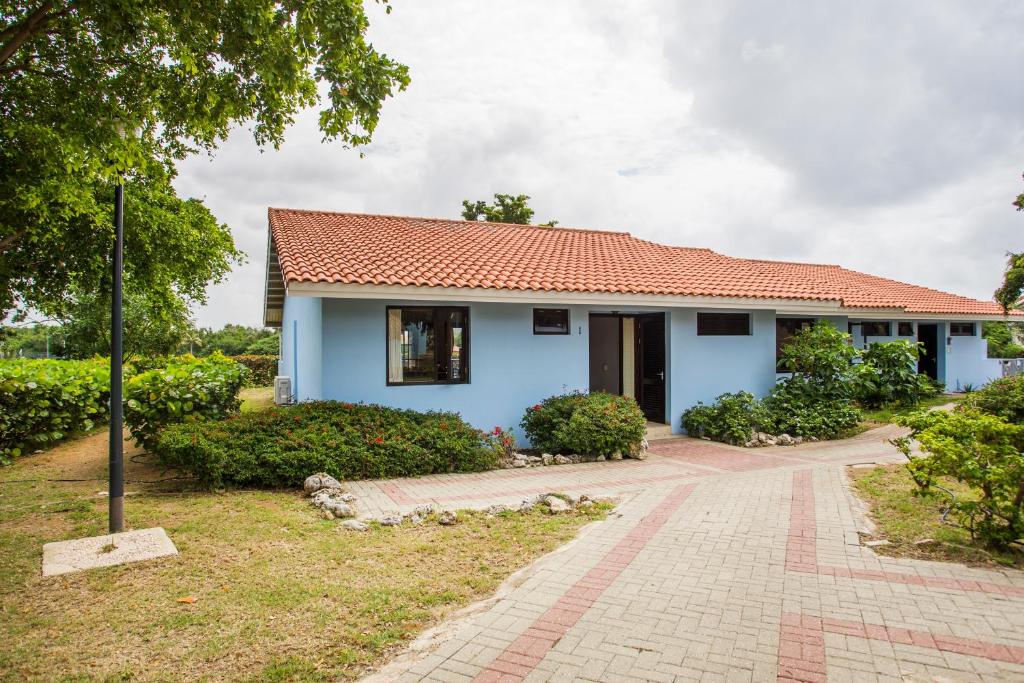 a blue house with a red roof at Cozy Bungalow in the Tropical Gardens of Blue Bay in Blue Bay