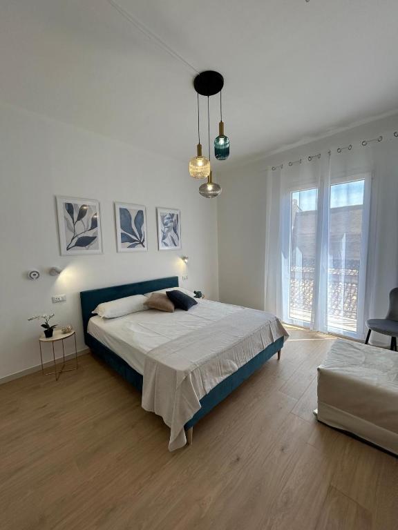 a white bedroom with a bed and a large window at Antò 2.0 in Castellammare del Golfo