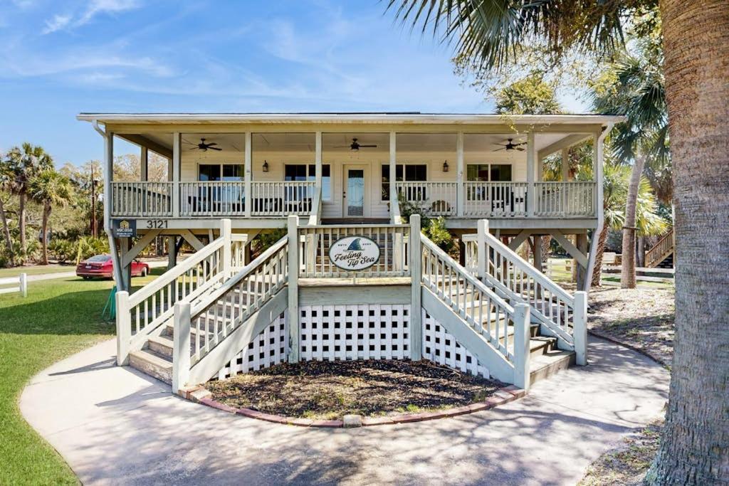 a large white house with a porch and a palm tree at Feeling Tip'Sea in Edisto Island