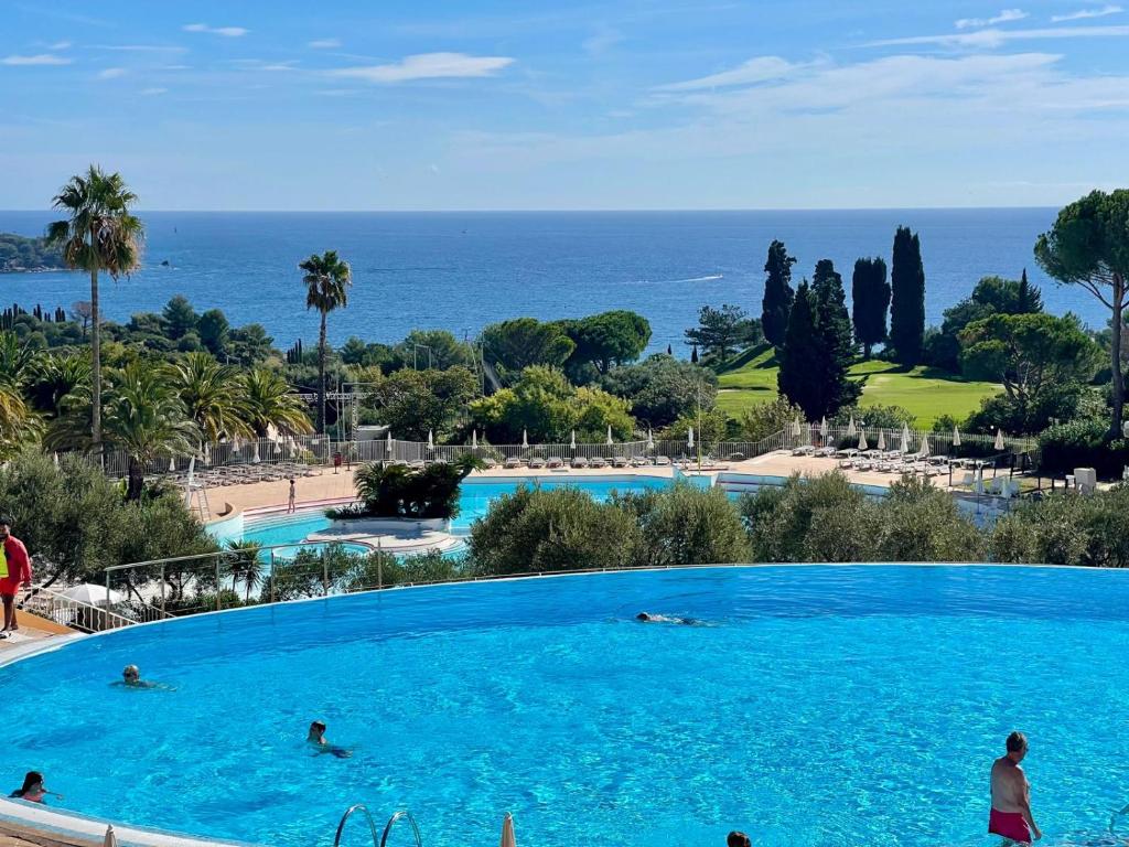 a large swimming pool with people in the water at Magnifique vue mer - 2 pièces climatisé avec terrasse à Cap Estérel in Saint-Raphaël