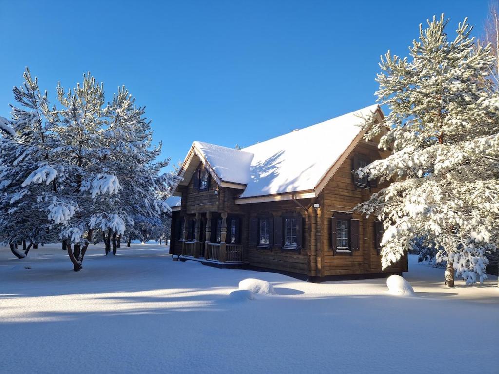 a log cabin in the snow with snow covered trees at Sodyba Vovierių slėnis in Kuras