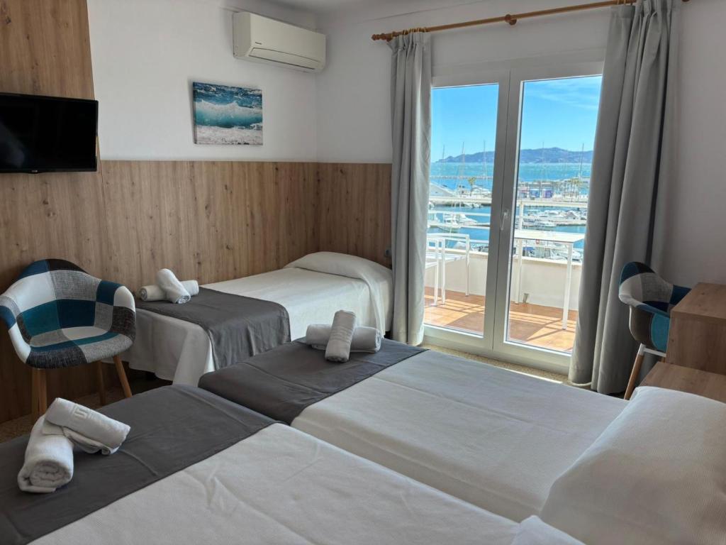 a hotel room with two beds and a large window at Hostal Santa Clara in L'Estartit
