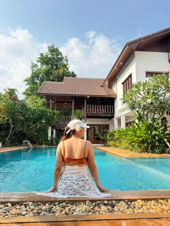 a woman sitting next to a swimming pool at Clear Water Pool Villa in Mu Si