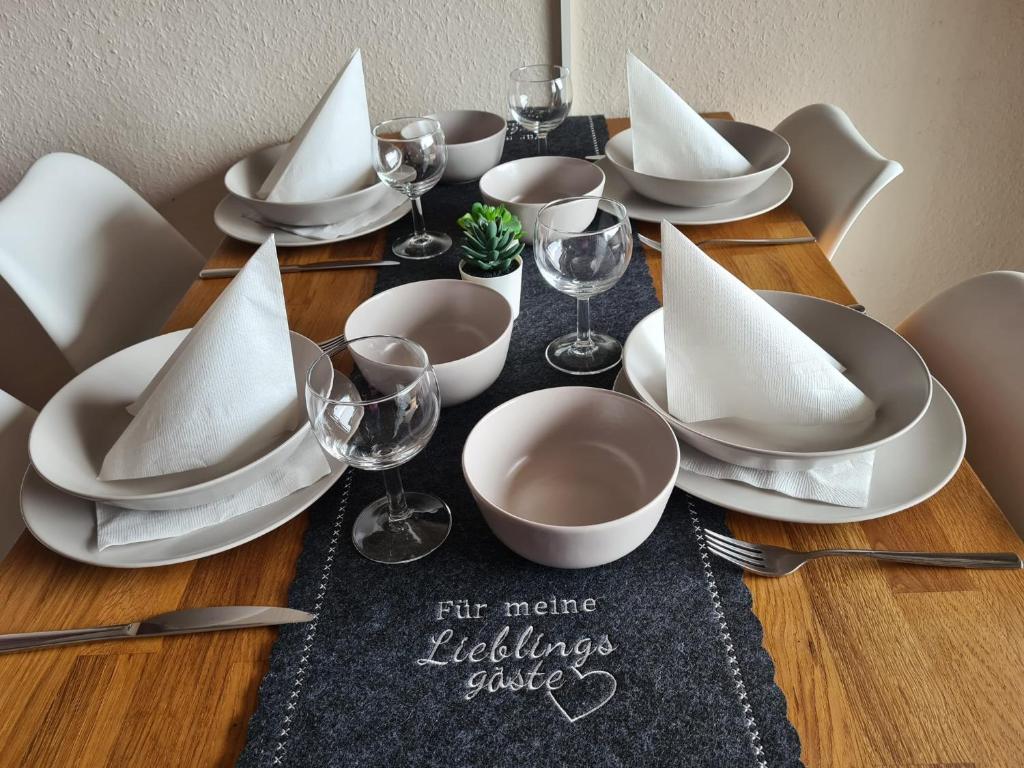 a table with white plates and wine glasses on it at Schwarzwald Heimat mit Pool, Sauna in Schönwald
