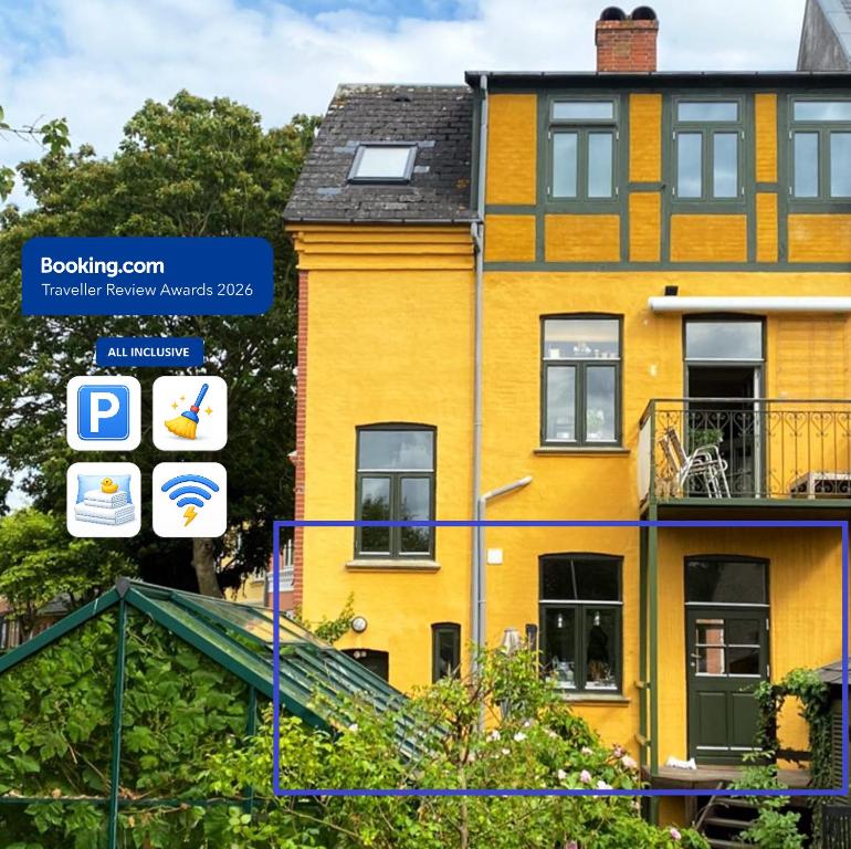 a yellow house with a sign in front of it at City House with Terrace, Garden and Free Parking in Odense