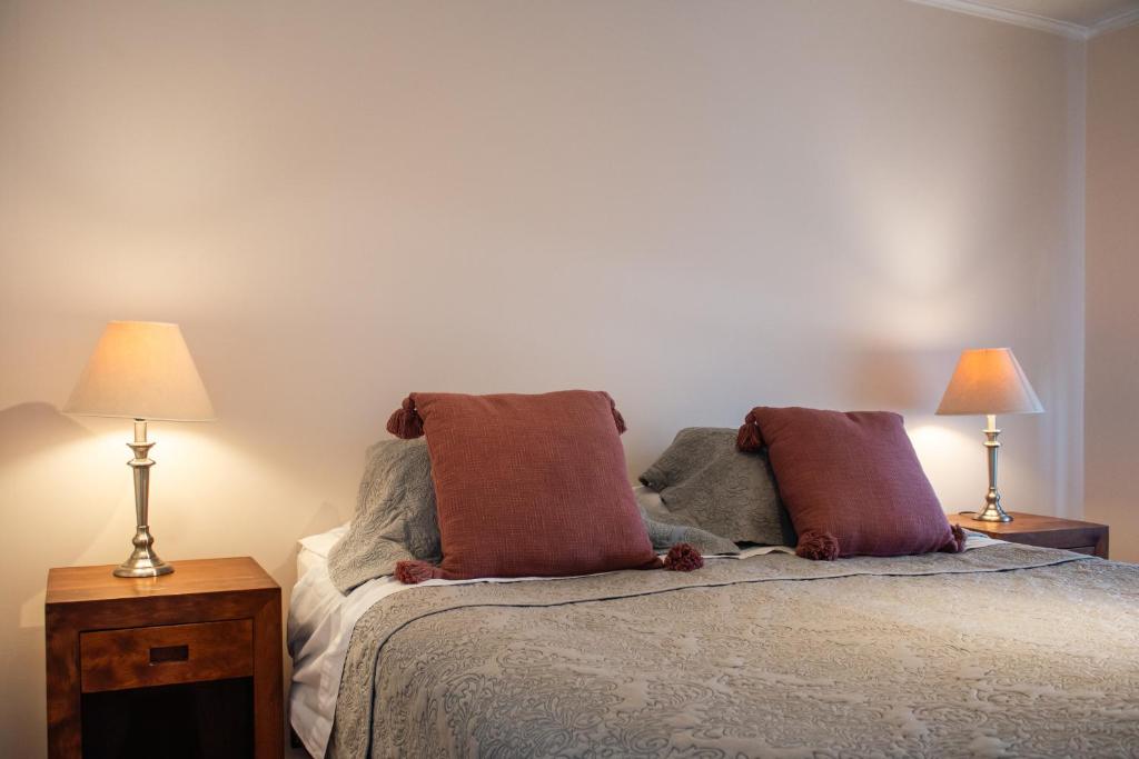 a bedroom with a bed with two lamps on it at Apart Hotel Plaza Centro in El Cerrillo