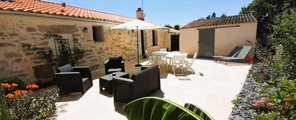 a patio with a table and chairs and an umbrella at Gîtes Arvor et Tevenn in Saint-Brevin-les-Pins