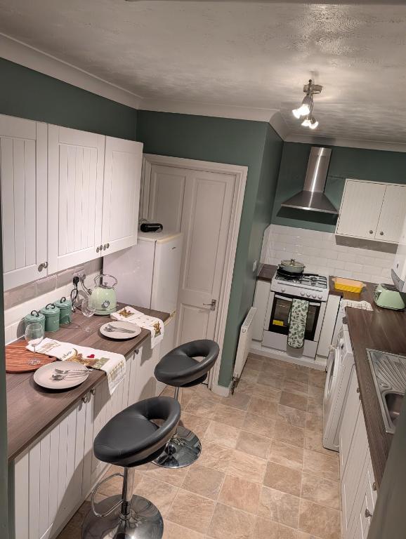 a kitchen with white cabinets and black stools in it at Affleck Street in Gateshead