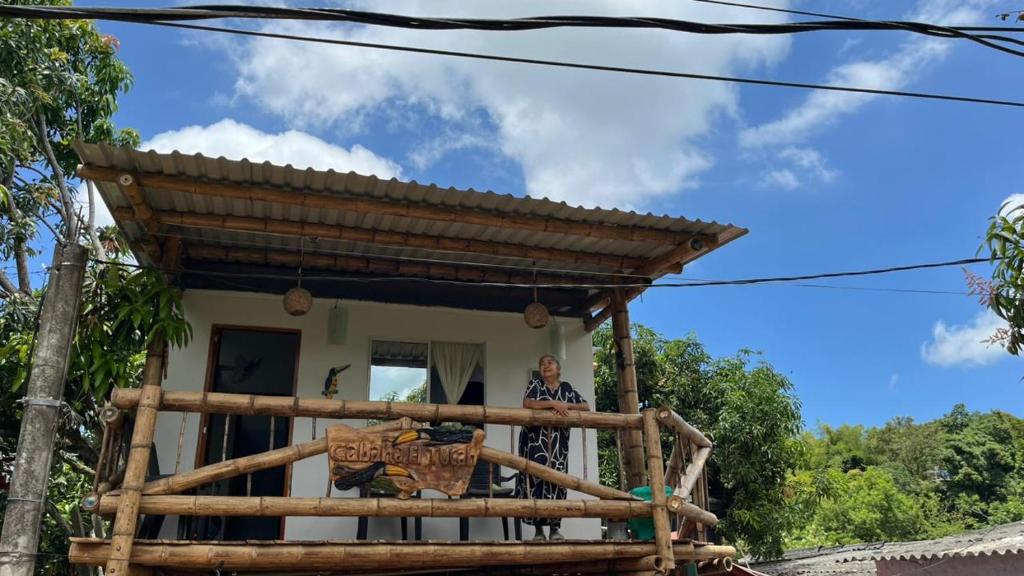 a woman standing on the porch of a house at Cabaña El Tucan in Minca