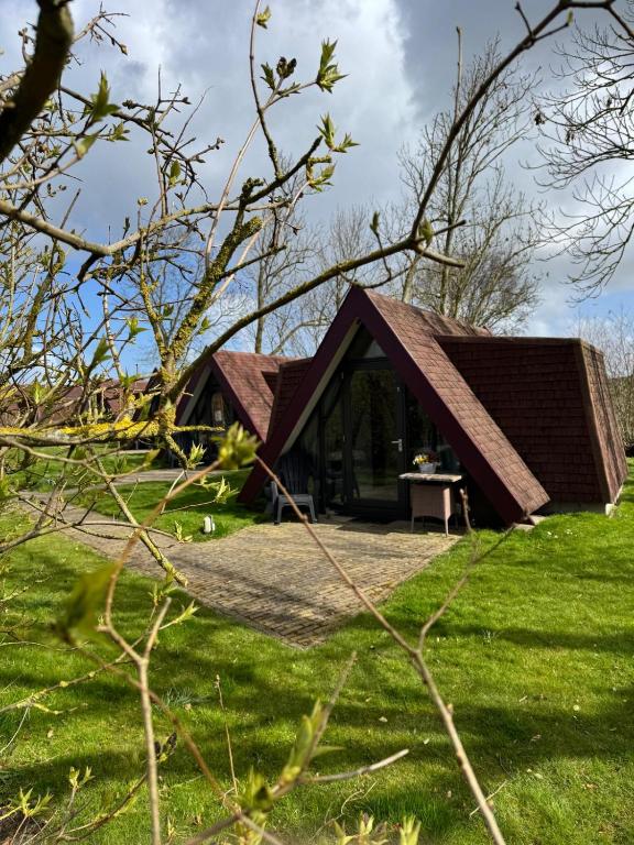 a house with a pitched roof in a field at Hotelhuisjes Oosterleek in Oosterleek