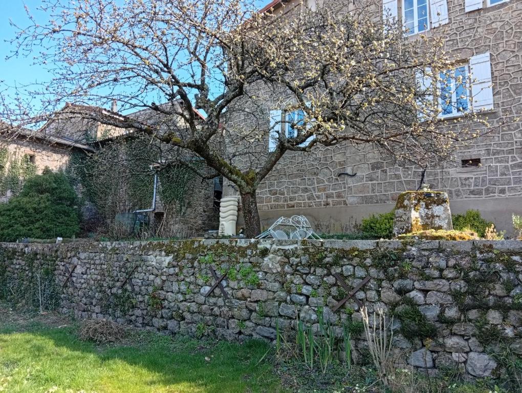 a stone wall with a tree in front of a building at Les Lavandières in Satillieu
