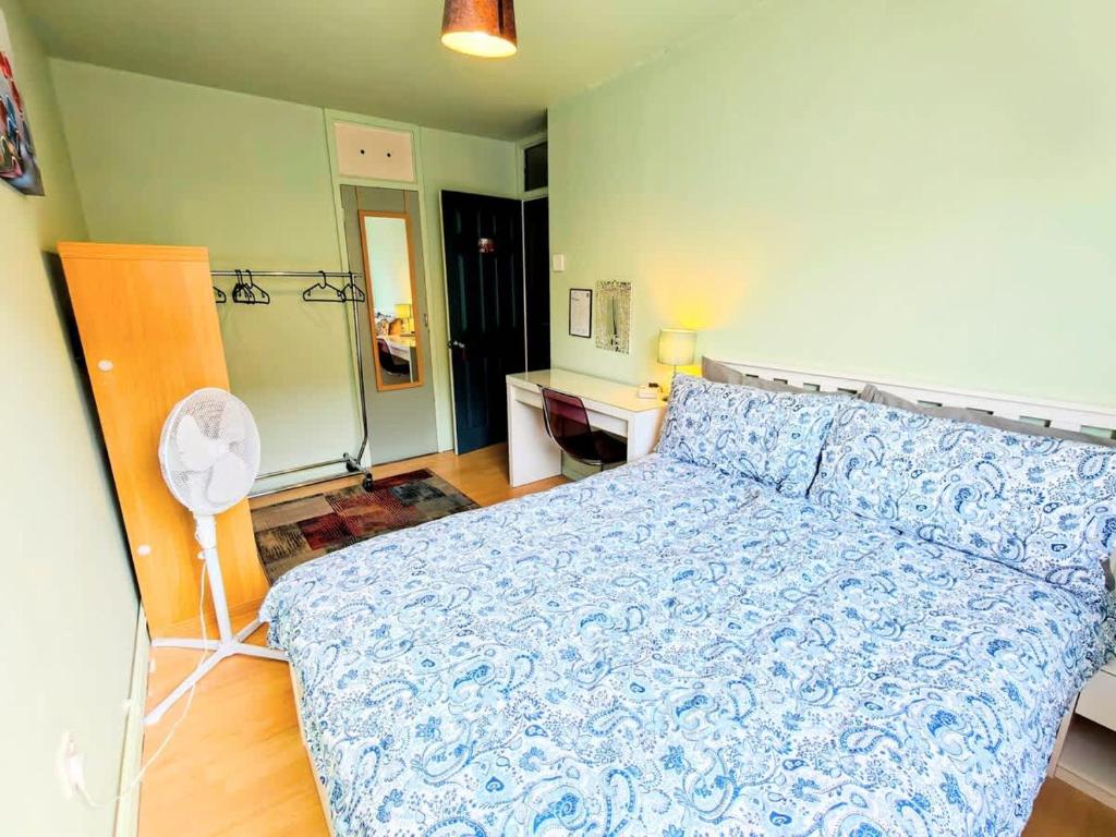 a bedroom with a bed with a blue bedspread and a fan at Spacious Double Room - Shared Bathroom - Zone 2 - Smart Lock Entry - No Check In Hassle in London