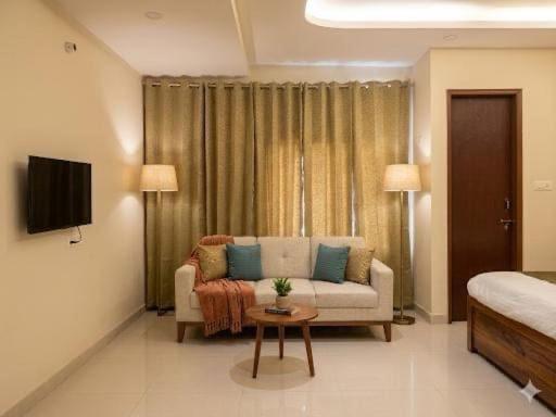 a living room with a couch and a tv at Super Townhouse HOTEL SPR ROAD in Gurgaon