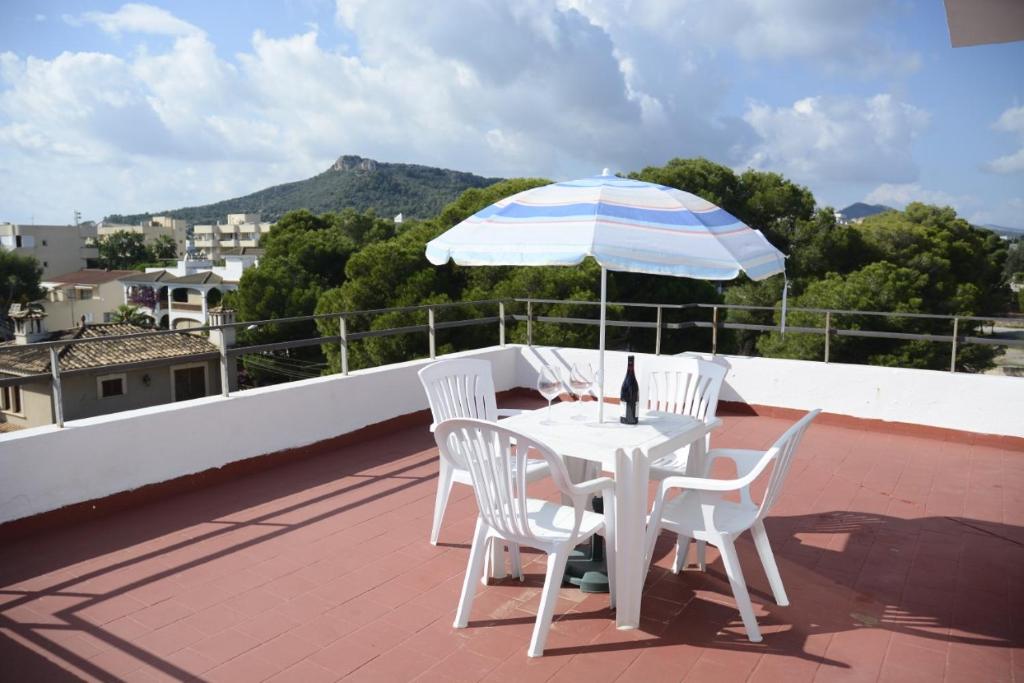 einen weißen Tisch und Stühle mit Sonnenschirm auf dem Dach in der Unterkunft Sa Marina in Cala Millor