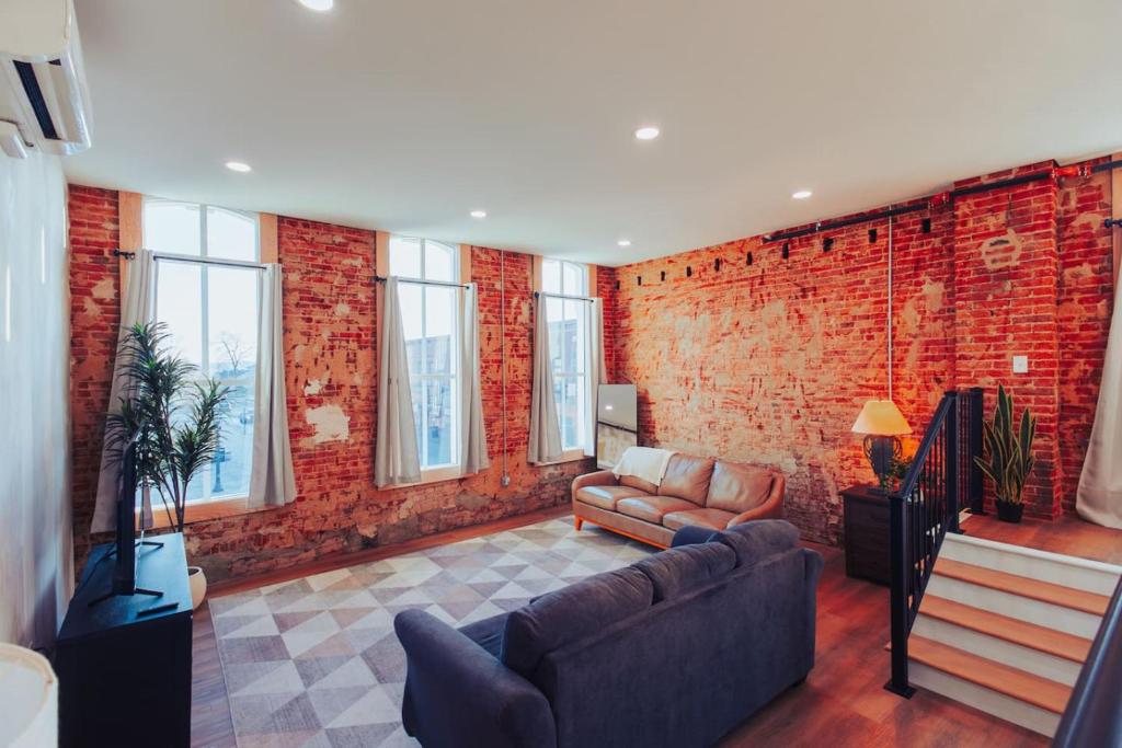 a living room with a couch and a brick wall at American Hall - Kaufman Suite in Millersburg
