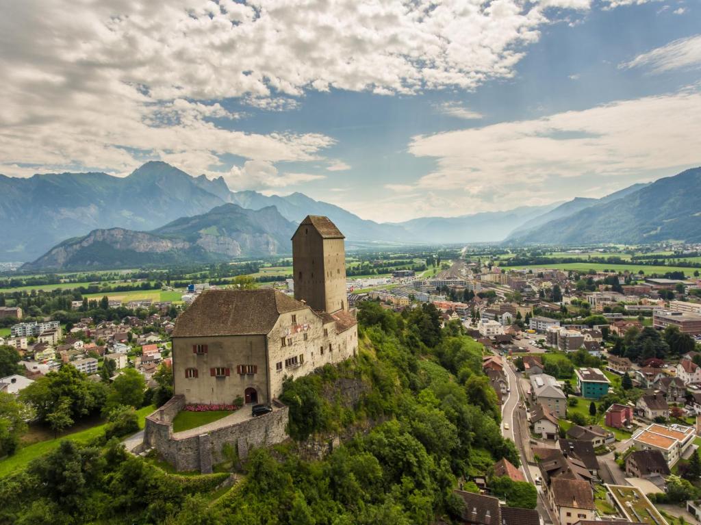 an old building on a hill with mountains in the background at Hotel Franz Anton in Sargans