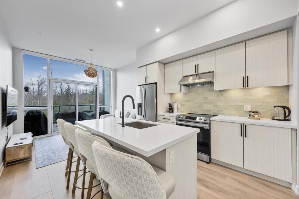Eine Küche mit weißen Schränken und einer Kücheninsel mit Stühlen in der Unterkunft Lake Simcoe Stays - Friday Harbour's Official Rental Program - Aspen Suite in Innisfil