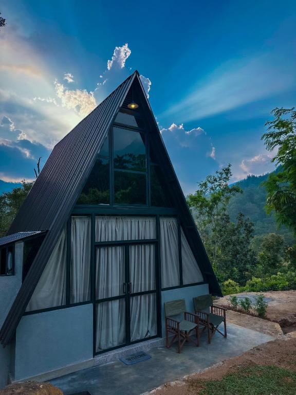 a building with a pitched roof with two benches at Alpine Heights in Kumburuteniwela