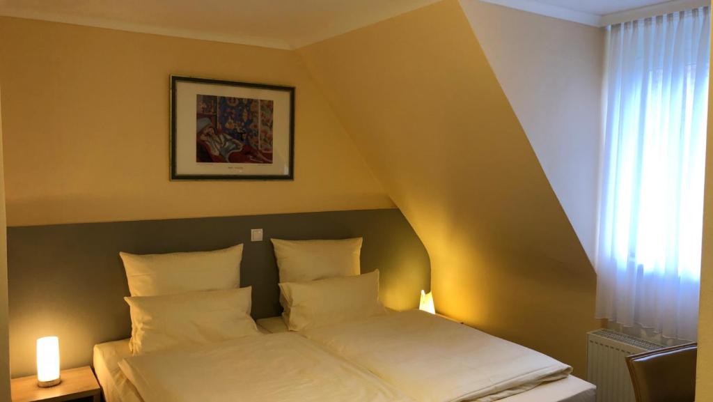 a bed with two pillows in a room at Löns Hotel Garni in Garbsen