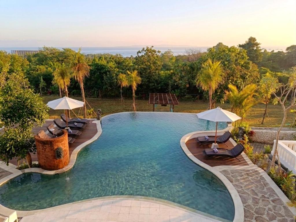 a large swimming pool with chairs and umbrellas at Sardja Uluwatu in Uluwatu