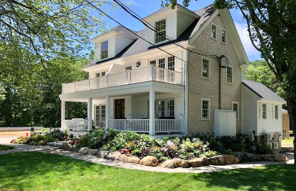a large white house with a porch and flowers at Stars And Stripes in Kennebunkport