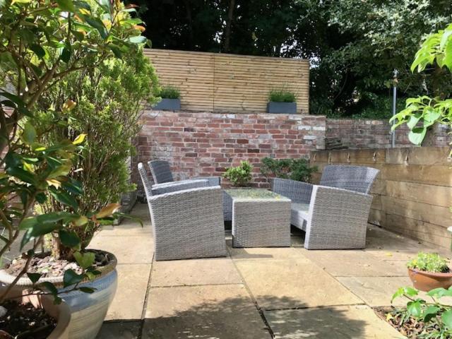 a patio with four chairs and a table and a brick wall at Stunning 3 bed house by Endcliffe Park in Nether Edge