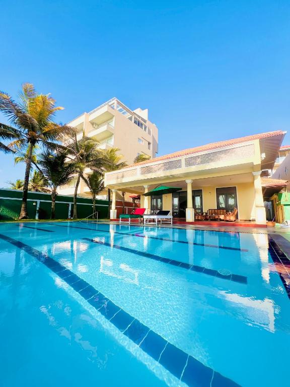a swimming pool in front of a building with palm trees at Sunset Point Beachfront Villa & Restaurant in Negombo