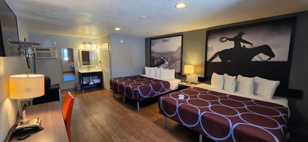 a hotel room with two beds and a large painting on the wall at Super 8 by Wyndham Sonora in Sonora