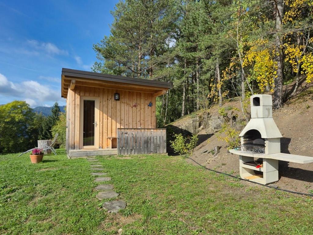 a small cabin with a grill in the grass at Glamping Gril in Ljubno