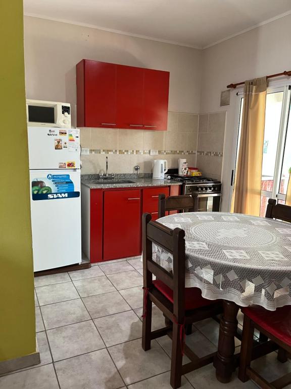 a kitchen with red cabinets and a white refrigerator at El Buen Descanso in Gualeguaychú