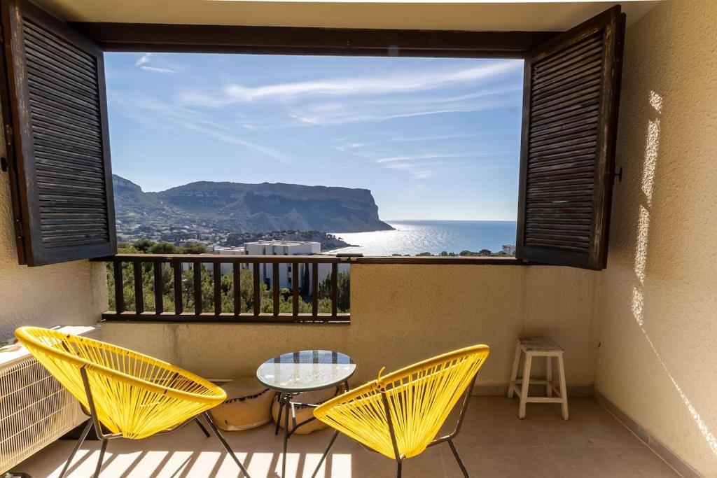 a balcony with a table and chairs and a view of the ocean at Face a la mer Cassis in Cassis