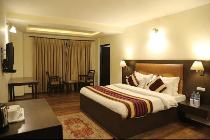 a hotel room with a large bed and a desk at Hotel Sandhya in Kasol