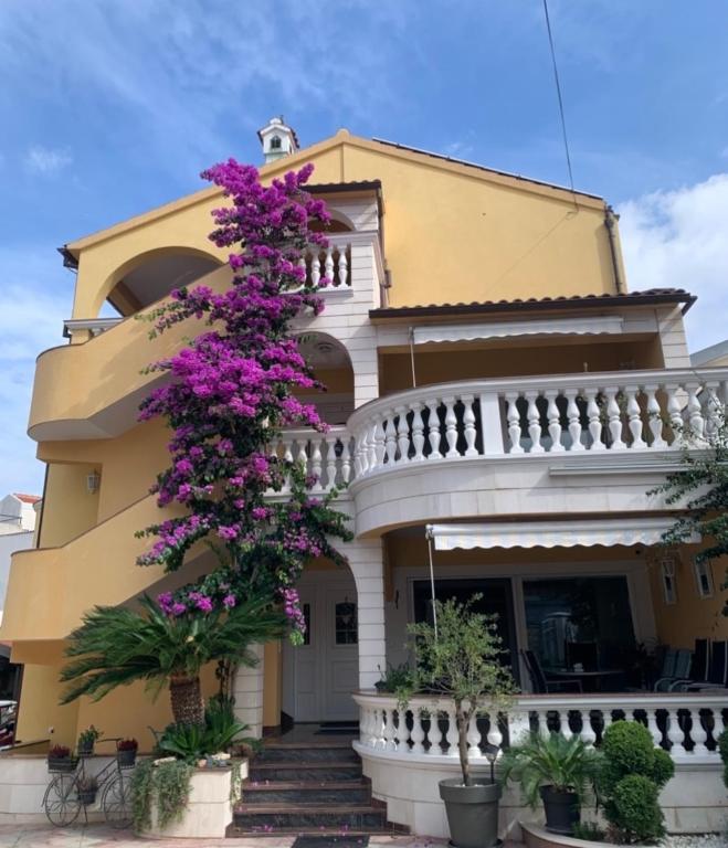 a yellow building with purple flowers on it at Apartments Visnja in Vodice