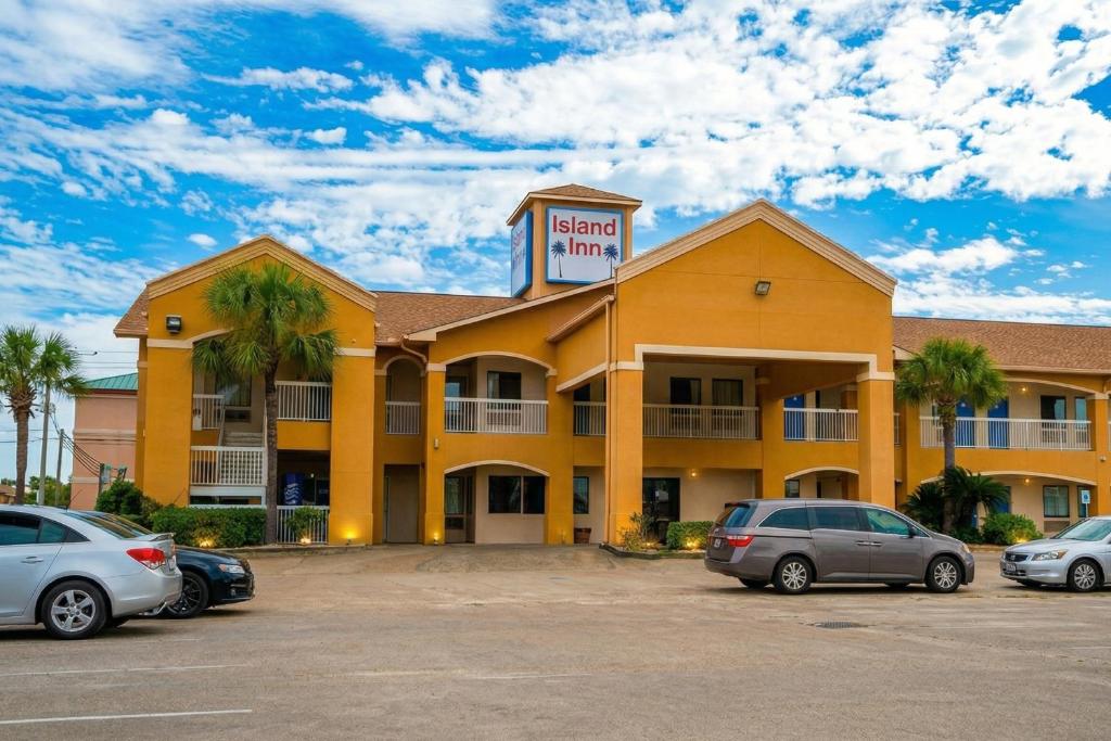 a hotel with cars parked in a parking lot at Island Inn By OYO Galveston Beach, TX in Galveston