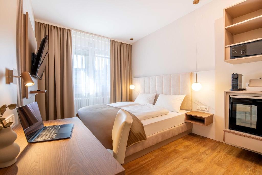 a bedroom with a bed and a laptop on a desk at Altstadt Hotel in Würzburg