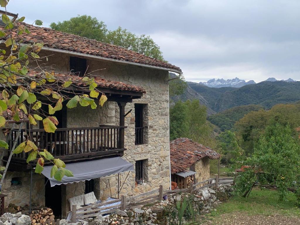 a stone house with a balcony and mountains in the background at Casa de Aldea EL Fusu in Taranes