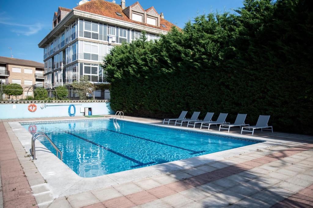 ein Schwimmbad mit Stühlen und ein Gebäude in der Unterkunft BLUESEA Noja in Noja