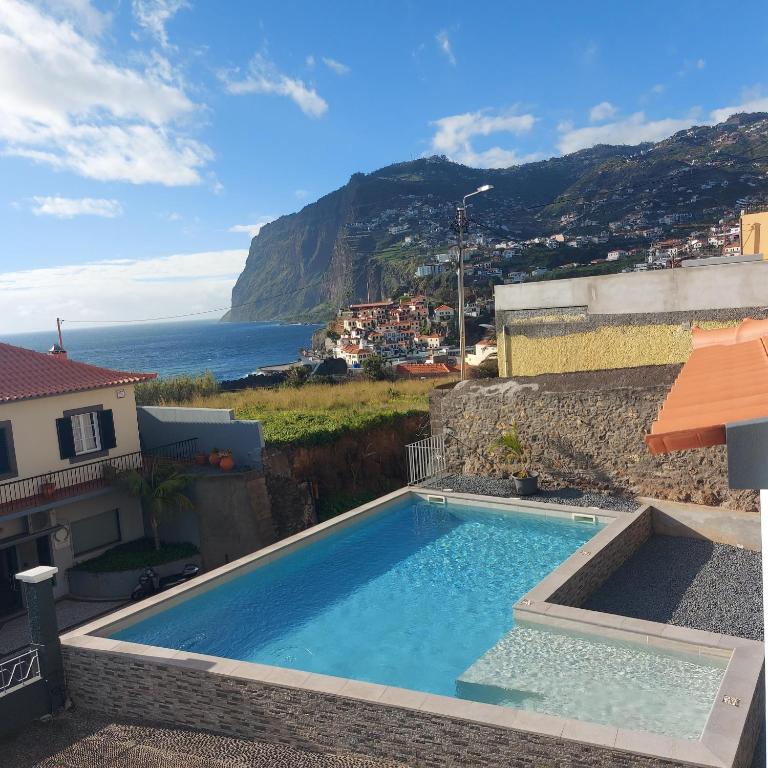 a swimming pool with a view of the ocean at Maria's House in Câmara de Lobos