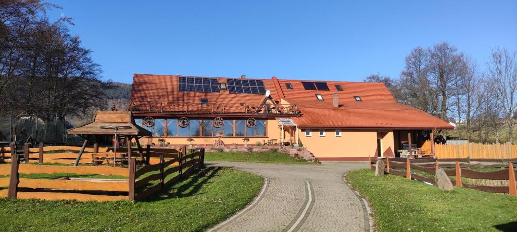 a building with a red roof and a dirt road at Agroturystyka Gościniec Ethoria in Łomnica