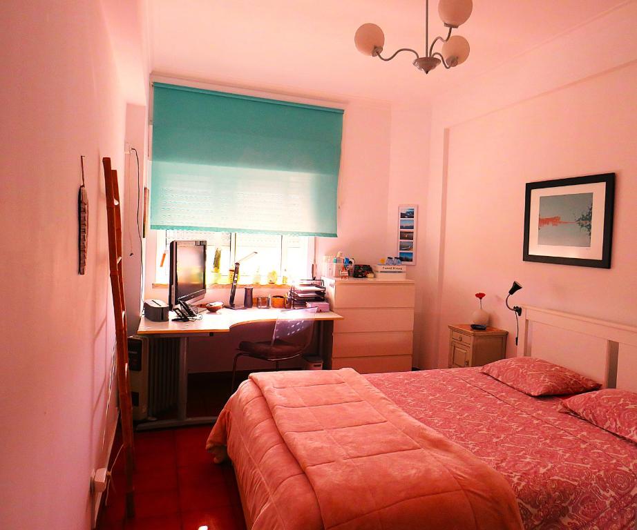 a bedroom with a bed and a desk and a window at Al-Madan in Almada
