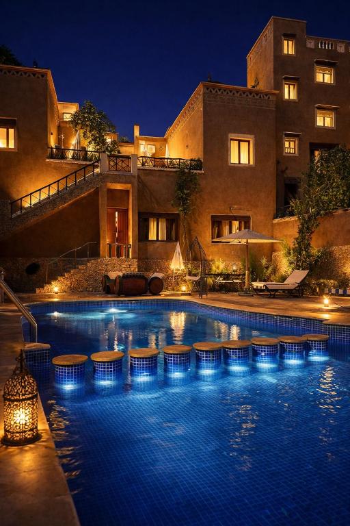 a swimming pool in front of a building at night at Riad Des Vieilles Charrues in Boumalne Dades