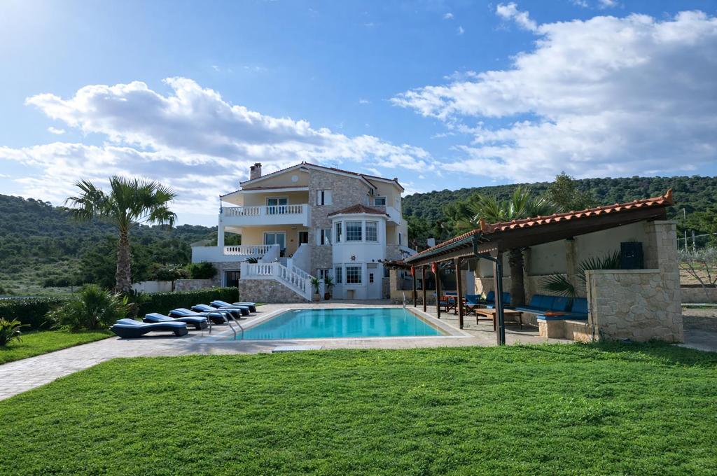 a large house with a swimming pool in front of it at Bella Villa with Private Pool & Sea View Ideal for Groups in Vaia